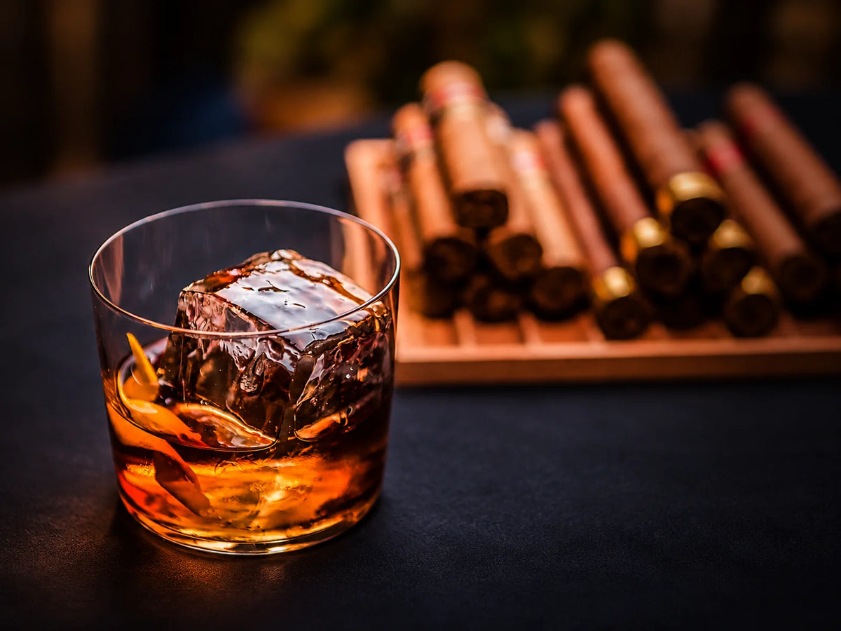 Whiskyglas mit großem Eiswürfel und Zigarren als Teil einer Spirits Experience bei Liquid Prodigy